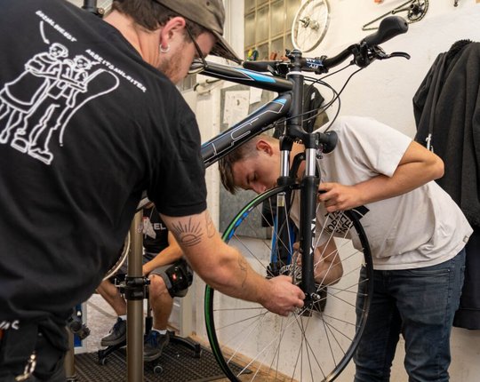 Matthias Kochmann und Flo inspizieren zusammen ein Fahrrad