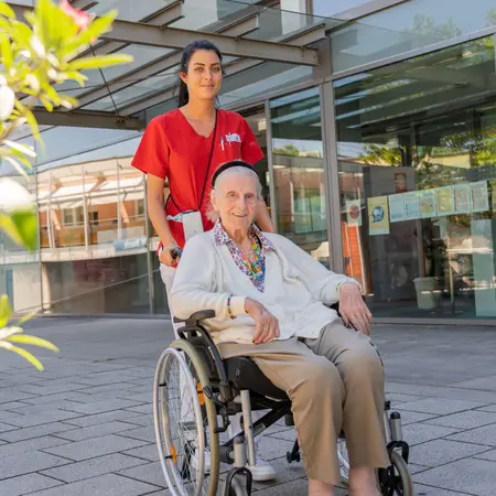 Altenpflegerin mit Seniorin im Rollstuhl